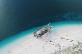 Aerial photo of a ship on a beach being worked on.