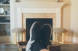 Two feet propped on a coffee table in a point-of-view shot of watching Netflix on TV