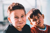 Two young boys scrunching up their faces