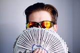 Guy in sunglasses, flashing a wad of $100 bills.