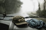 Driving in the rain, ball cap and t shirt on the dash