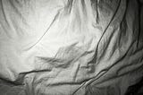 White bed sheets crumpled.