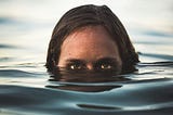 A woman’s head is visible in water up to her eyes.