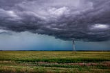 storm clouds looming over a solitary windmill in a field