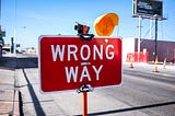 Rectangular red sign with Wrong Way written on it in white