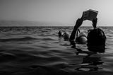 black and white photography, girl in the sea, holding a book, reading