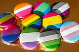 A variety of flags belonging to queer identities, on colorful pins.