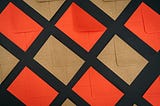 Orange and brown mails organized in a grid and laid diagonally in a checkboard fashion atop a black background.
