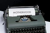 A typewriter with the word motherhood on the paper.