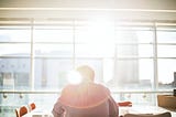 man sitting in front of sunny window in office