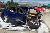 Crashed car on highway with entire front end missing, and fire suppressant foam all around.