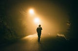 A man standing in fog under the street lights