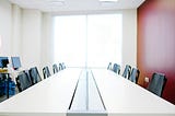A conference table with 12 chairs, clean surface, simple.