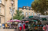 People shopping at an outdoor market in a small town in France.