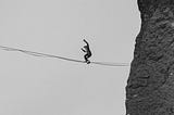 A tightrope walker focuses on keeping his balance as he makes his way across a void