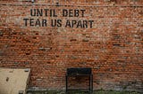 A brick wall with the message: Until Debt Tear Us Apart