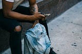 A man sitting outside a shop reading messages on his new phone