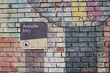 Brick wall with sign that says accessible entry