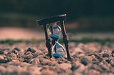 An hourglass resting in beach sand.