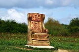 Ornately carved wooden chair in an empty field.