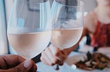 Two wine glasses are being held and clinked together.