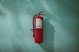 A fire-extinguisher hangs from a blue wall.