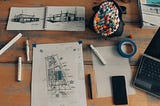 Architectural sketches, including perspective drawings and a plan laid out on a desk