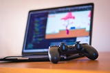 Indie game developer testing their game with a game controller on their laptop.