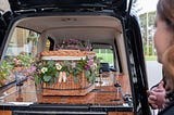 Looking at a casket in the back of a hearse
