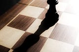 A black chess piece on a wooden chessboard