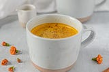 Golden milk, topped with connaom in a white mug