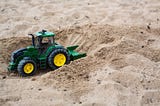 A toy truck scoops a path through sand