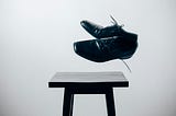 A pair of men’s shoes, floating in mid air above a small table