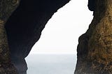 An ocean archway made of stone — in daytime.