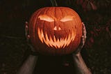 A man holding a carved pumpkin.