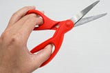 A left hand using scissors designed for the right hand.