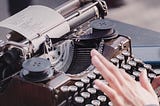 Person typing on antique typewriter.