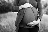 A picture of a pregnant woman’s stomach, with the woman’s hands resting on her belly.