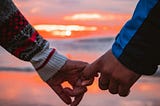 Closeup photo of a man and woman holding each other’s pinky fingers