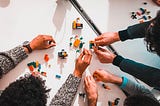 Picture of 3 people’s hands building and playing with Legos