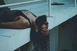 A bearded man lying on a ledge with a distant expression, symbolizing disconnection and emotional fatigue