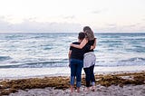 a mother and son at the beach, watching the waves.