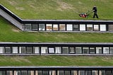 A person mowing a roof lawn on a multi level building