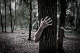 Black and white image of a tree with a hand and arm coming around it