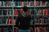 man standing in front of a filled book shelf