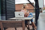 a woman sitting at a cafe table and computer drinking tea