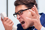 Man looking angrily at a phone and screaming.