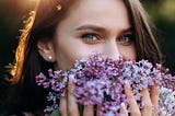 Beautiful green eyed young woman holding flowers to her face