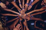 A bunch of people touching hands in a circle.