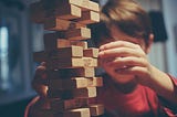 A young boy tries to balance cubes of woods to buid a castle